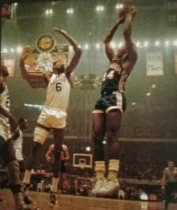 Celtics great Bill Russell hoists a hook shot over the outstretched arm of an LA Lakers defender.
