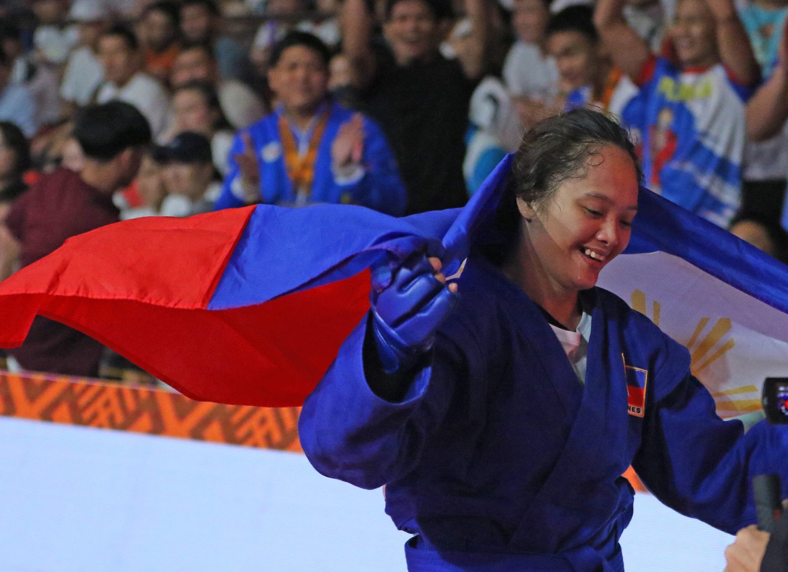 Princess Aumagel Cortez smiles as she drapes the Philippine flag over her shoulders after clinching the 59kg women's class combat sambo gold in the 11th Asia-Oceania Sambo Championships at the Ninoy Aquino Stadium last Saturday evening. [PSC photo]