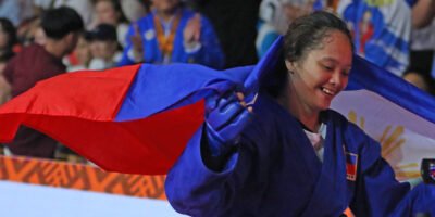 Princess Aumagel Cortez smiles as she drapes the Philippine flag over her shoulders after clinching the 59kg women's class combat sambo gold in the 11th Asia-Oceania Sambo Championships at the Ninoy Aquino Stadium last Saturday evening. [PSC photo]